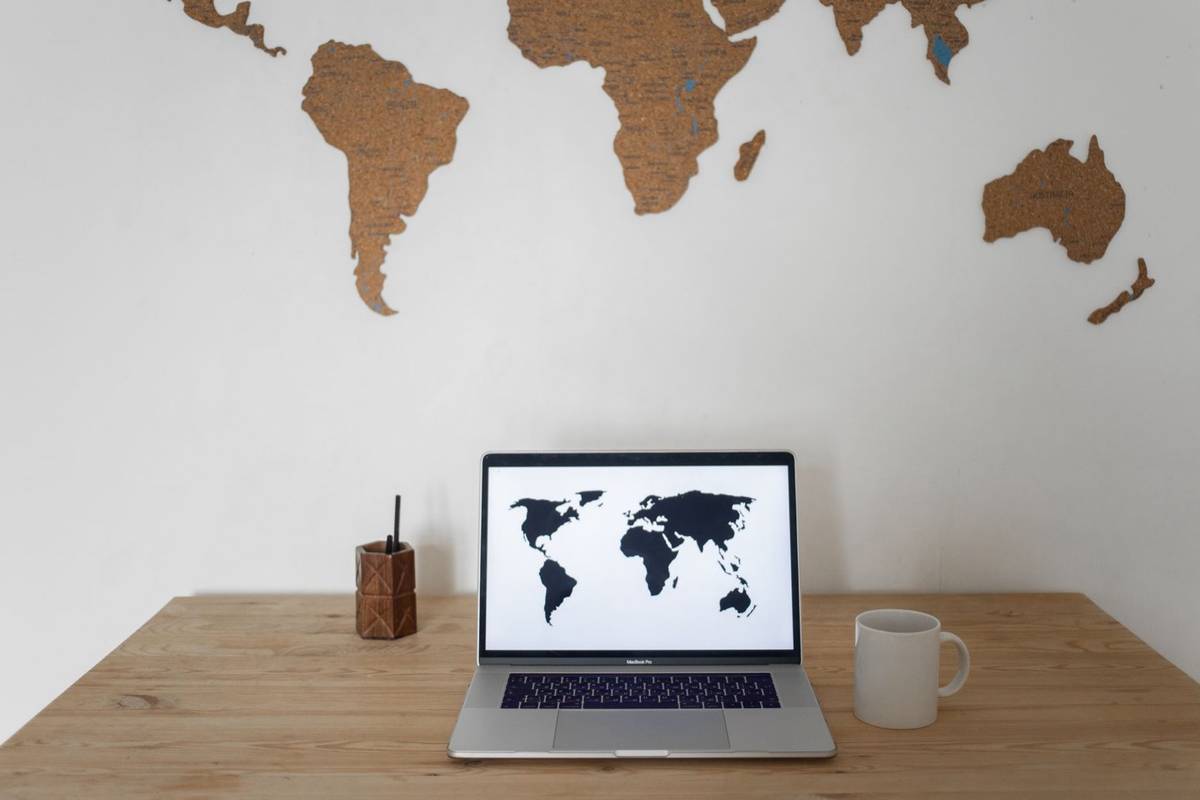 Laptop showing a map search results page on a desk next to blueprints